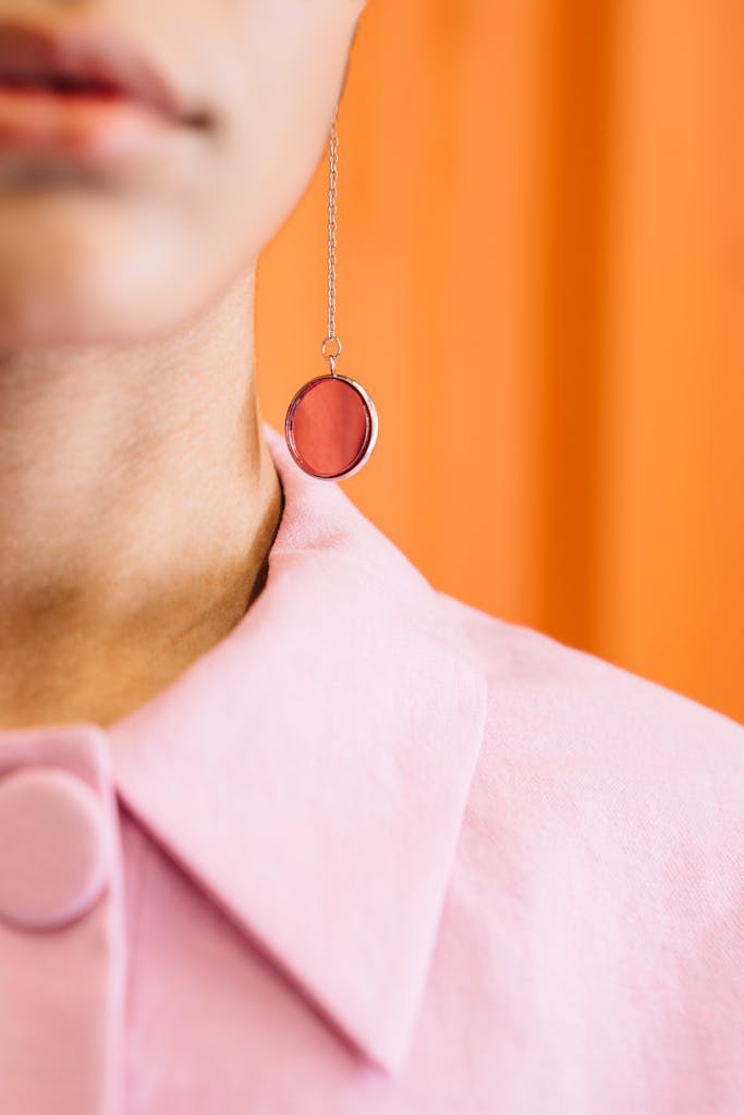 Close-up of a pink pretty stone or glass earring worn by a model in a studio shoot - delicate, statement jewellery
