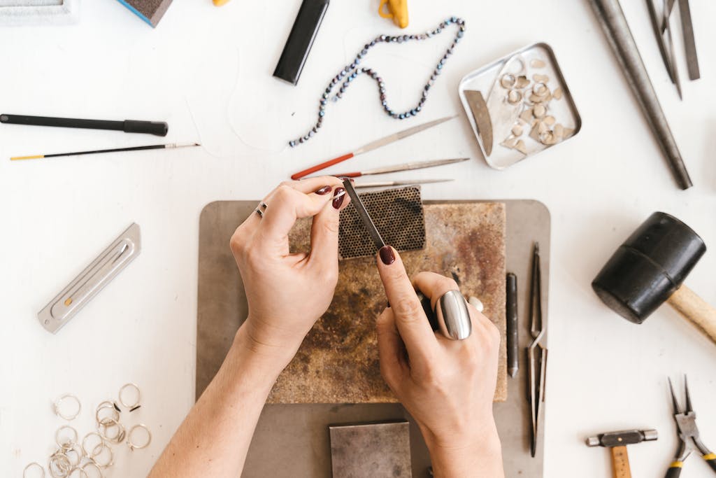 Artisan skillfully crafting jewelry with tools and materials in a creative workspace.