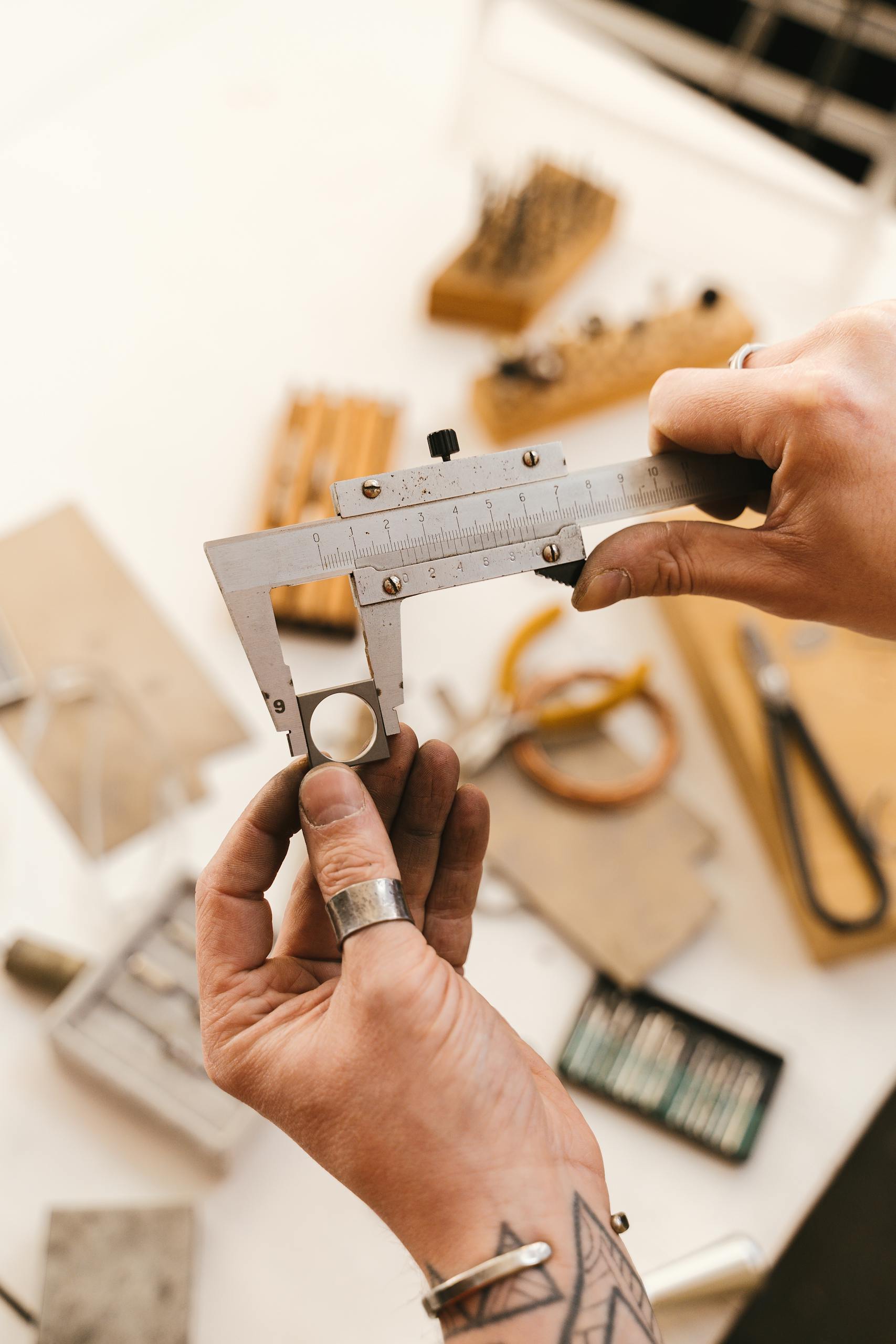 Close-up of hands using a caliper for precise measurement in a workshop setting.